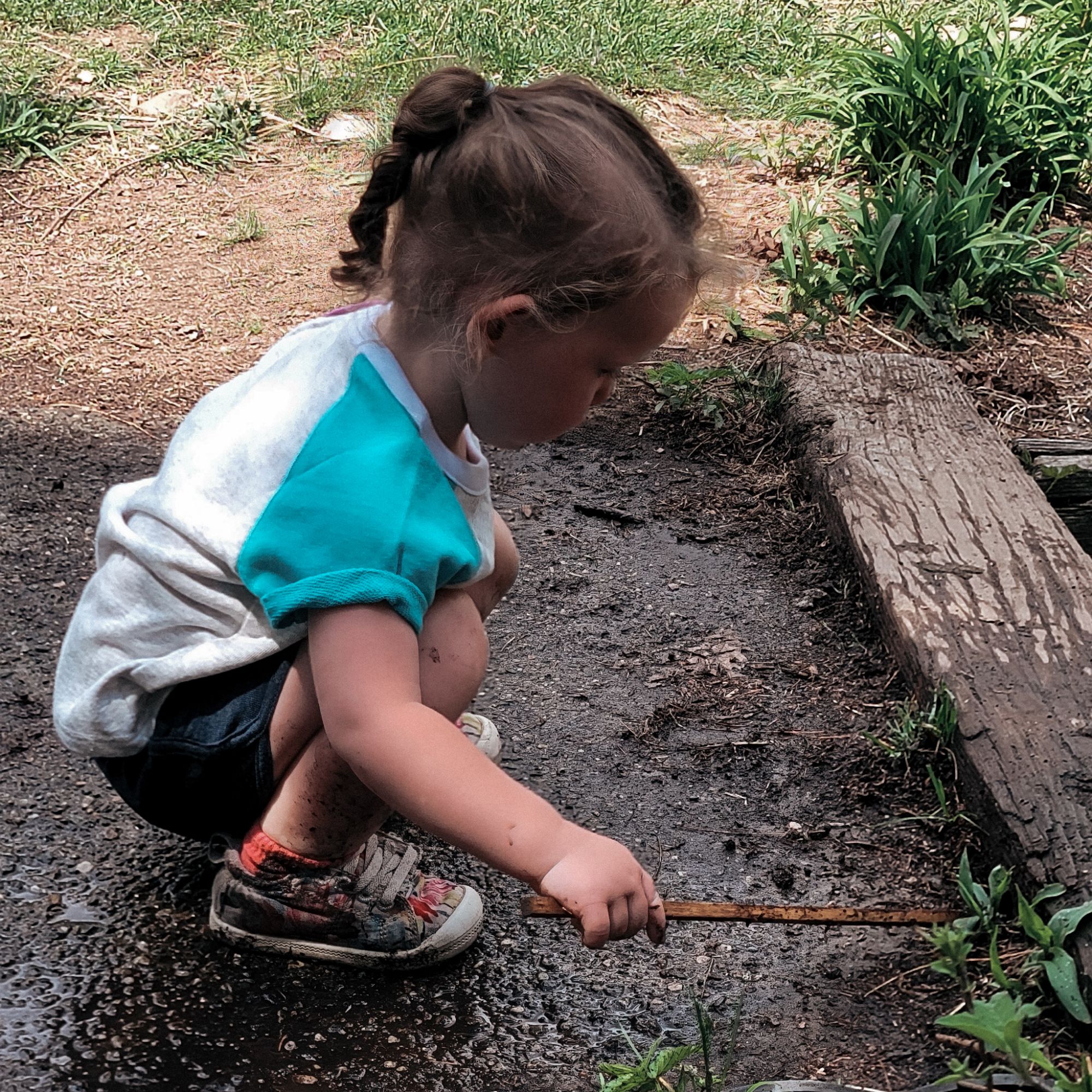 child playing with a stick in the mud